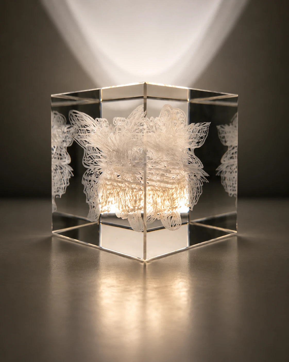 An angled view of the same crystal cube revealing the layered cocoon and butterfly engraving